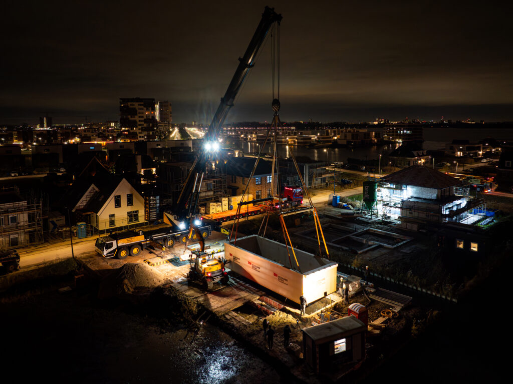 Prefab kelder wordt van de vrachtwagen afgetild door een kraan