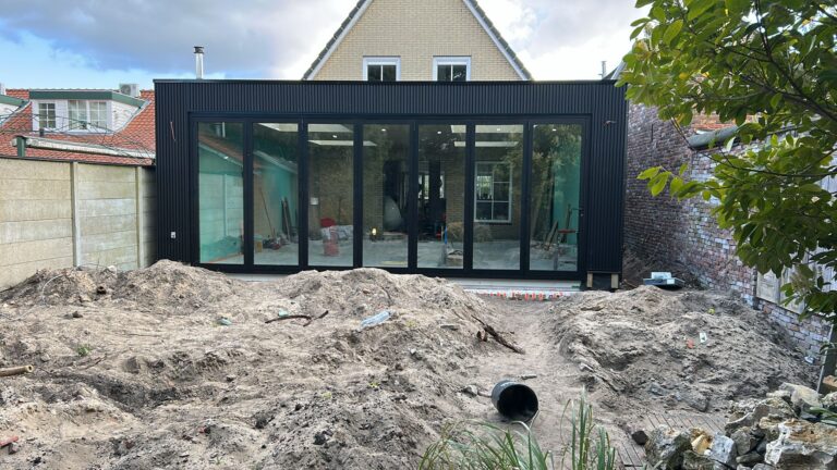 Moderne zwarte aanbouw in Zandvoort met een brede glazen vouwwand over vrijwel de volledige achtergevel.